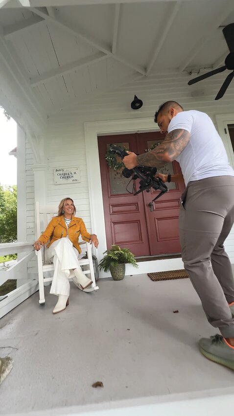 Kim Marion (left) smiles as she waits for videographer Javier Rosa to set up his equipment, ready to perform her customized version of Otis Redding’s classic “(Sittin’ On) The Dock of the Bay,” — part of a new marketing strategy for her real estate business.