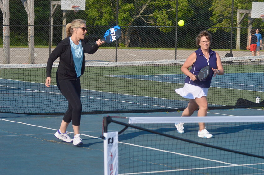 Kim Hassan (left) returns a shot as teammate Lois Miller looks on during pickleball league plat at Portsmouth High School on Thursday, June 12.