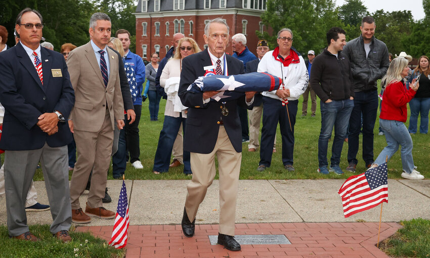 Chief Marshal Dick Devault carries the flag to the pole to be raised at Flag Day ceremonies on Saturday, June 14.