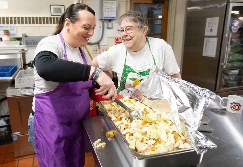 Program manager, Erica Harris (left) and long-time volunteer Margie Sousa prepare a corned beef and cabbage meal at the Good Neighbors food kitchen in Riverside on Monday, St. Patrick's Day. 