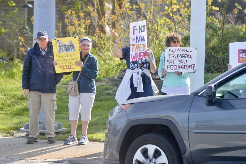 Protesters display signs at passing motorists during rush hour on Thursday, May 1, in Portsmouth.