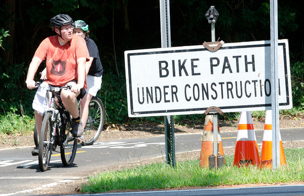 Bicyclists ride along the East Bay Bike Path, approaching the intersection with Middle Highway in Barrington.