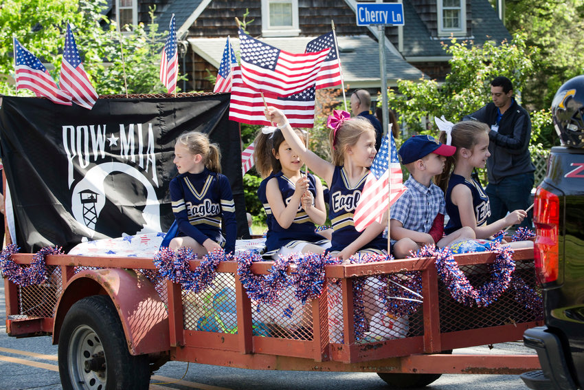 Barrington Pop Warner cheerleaders wave flags as they parade on a float during a previous Memorial Day parade.