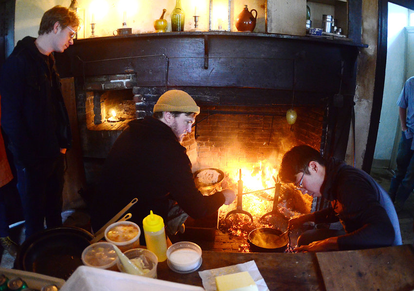 Restaurant owner Ben Sukle (middle) and John Ho (right) cook a meal on an historic open hearth for his Birch and Oberlin employees at Coggeshall Farm on Tuesday.