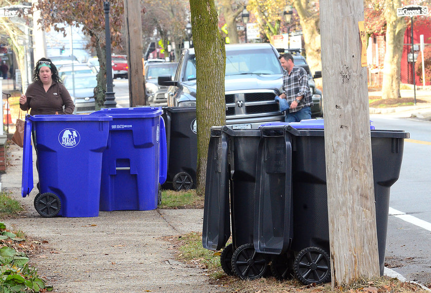 Warrren just launched its new trash and recycling program this week, similar to what Bristol plans for next spring. Pedestrians, bins and cars are shown here on Main Street in downtown Warren. Bristol has decided not to buy these bright blue bins, and it will offer residents smaller version, if they choose.