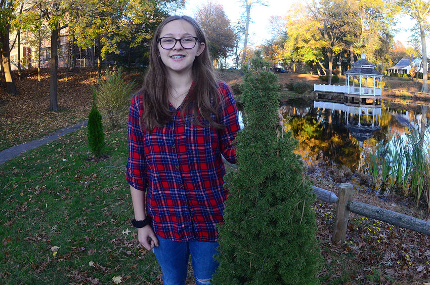 Barrington's Emma Marvelli stands beside one of the new trees planted at the Woods Pond property this fall. Emma shared news of the tree planting effort, which was part of her Girl Scout Silver Award community service project.