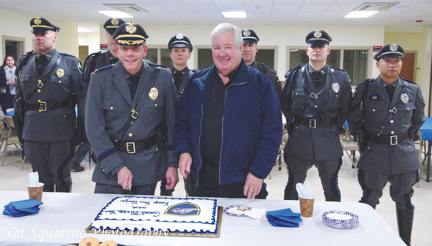 Bristol Police Chief Kevin Lynch and Father Barry Gamache ceremonially cut a cake at St. Mary&rsquo;s Church, with the backing of the Bristol Police Honor Guard.