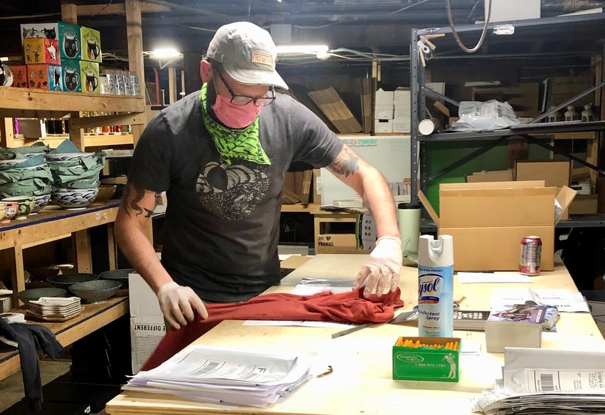 Asher Schofield bags T-shirts for delivery Thursday afternoon. His Frog and Toad store has sold more than 5,000 of them so far.