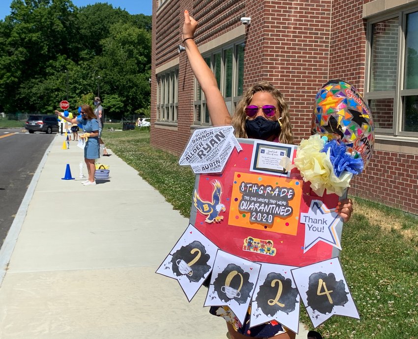 Red cluster teacher Stephanie Bannon cheers on eighth-graders as they pass by with their parents in their cars during a drive-by event at Barrington Middle School on Wednesday morning, June 17.