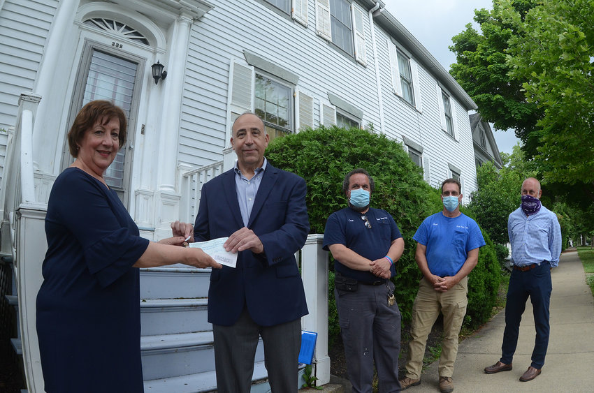 Diane Medeiros (left), executive director of East Bay Community Development Corp., accepts keys to the residence at 330 High St., former home of the late Richard Simpson, from attorney Joe Proietta on Tuesday. Joining them for the ceremonial transfer are East Bay CDC employees Curt Jouett and Frank Spinella, and consultant Scott Charpentier (far right).