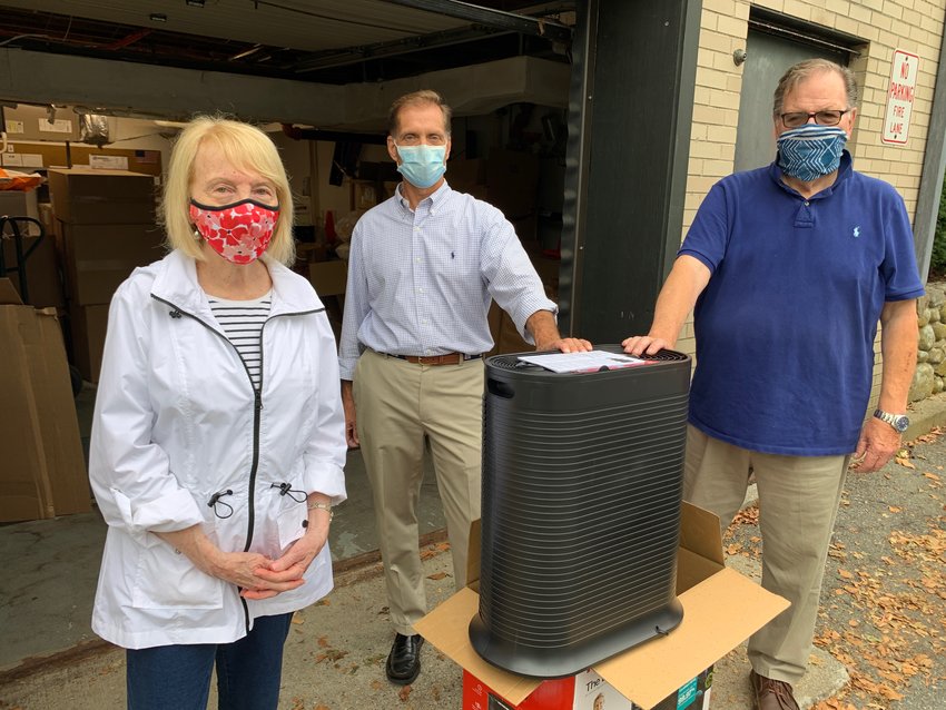 Adele Carlson (left) and her husband Gerald (right) present Barrington Superintendent of Schools Michael Messore with one of the air purifiers. The Carlsons donated 10 air purifier units to the school department recently.