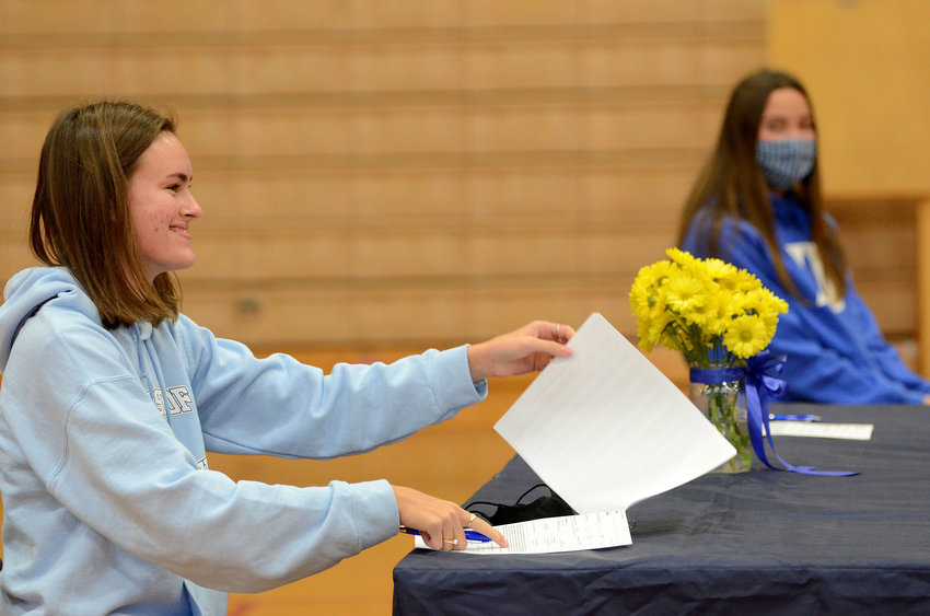 Barrington High School senior Ellie McGee signs a letter of intent to attend URI for rowing during a brief ceremony at Barrington High School earlier this month. At right is fellow BHS senior Tess Gagliano, who signed a letter of intent to play lacrosse at Duke University next year.