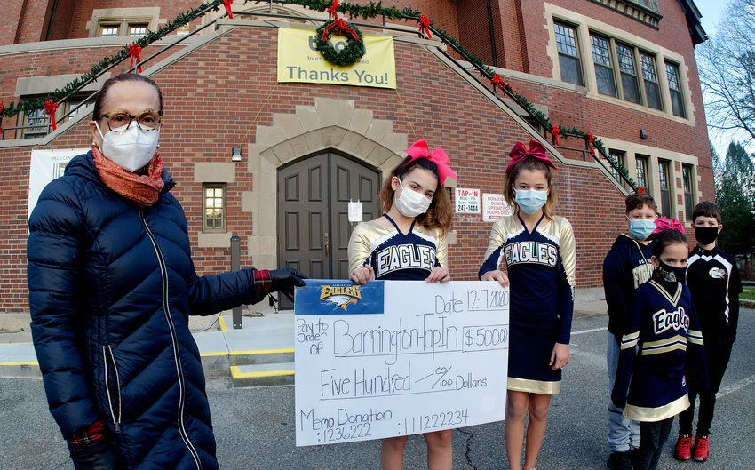 Tap-In President Tirza Rivera-Cira (left) receives a $500 donation from Barrington Pop Warner cheerleaders and football players Kaylin Hession, Addison Corrow, Macy Alexander, Trey Paup and Rian Hession on Monday afternoon.