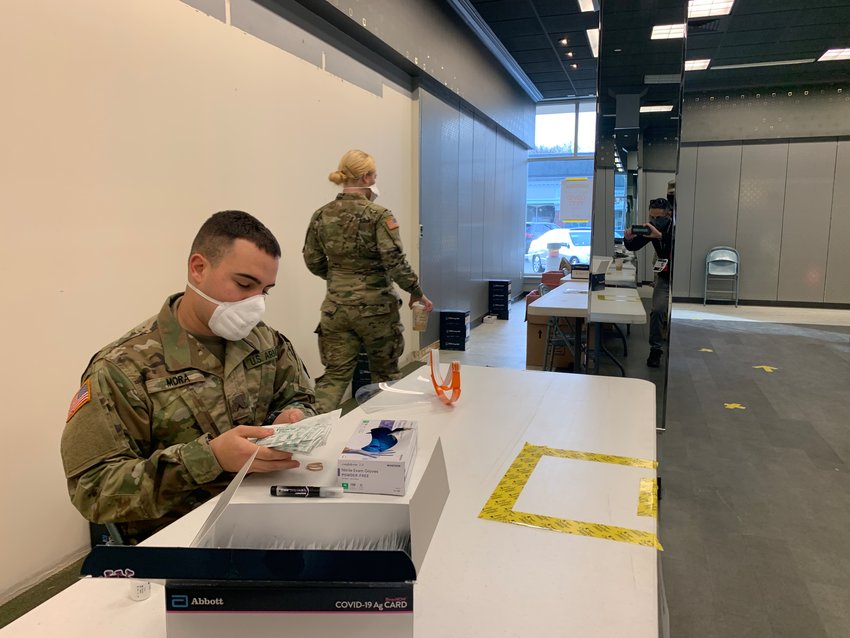 RI National Guardsman Darrien Mora readies packs of swabs at the pop-up testing site inside the Barrington Shopping Center on Tuesday morning.