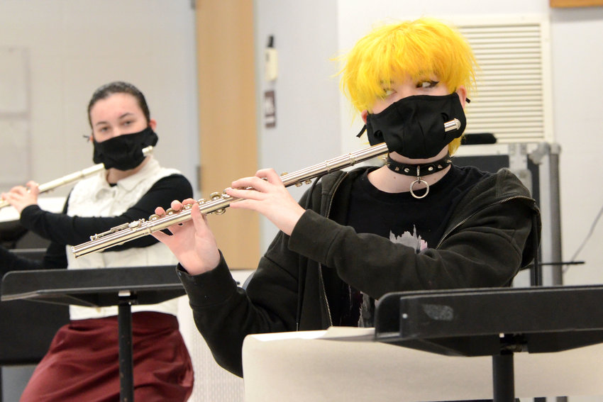 Isabelle Courtney (left) and Thomas Faulkner practice the flute using specially made masks during a concert band class on Tuesday morning at Mt. Hope High School. After not being allowed to meet or practice in person for nearly a year, music education students have resumed in-person classes &mdash; with restrictions.