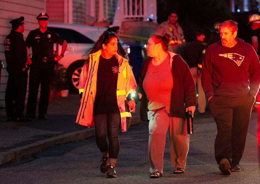 A firefighter walks 16a Prospect Street resident June Leone and her brother, Brian Jarvis, to a Red Cross truck for treatment Tuesday evening. Another resident of the three-family structure died when it caught fire.