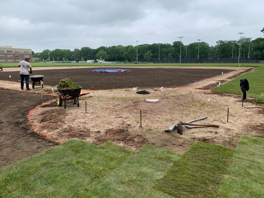 Workers install sod turf at the Barrington Middle School baseball field last week.