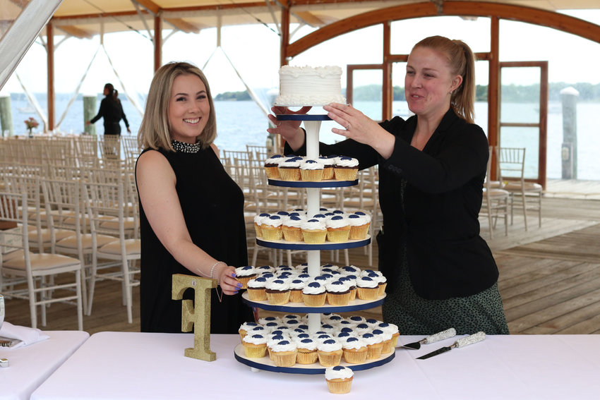 Brigh Finnegan (left) and Rebecca Vieira, director of banquets and events, put the finishing touches on the cake and desserts for&nbsp;a wedding held under the tent along Bristol Harbor on Friday.
