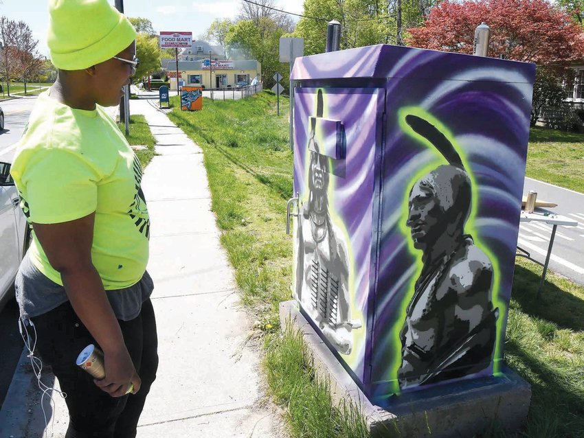 Artist Jessica Brown at work on her utility box painting at Main and Campbell streets. The phrase &quot;Land of the Pokanoket,&quot; not yet added by her in this photograph, was later painted over.