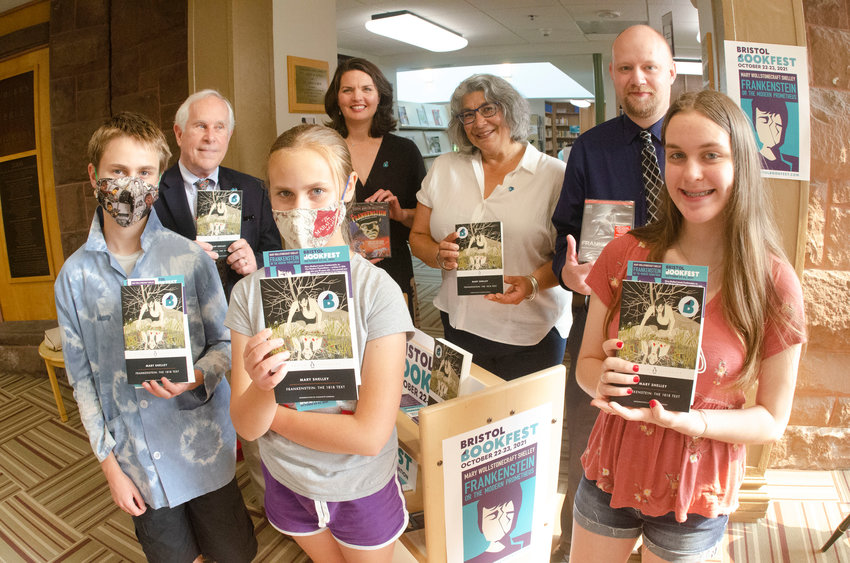 Youth readers Sampson Lombard, 13, (left), Fran Lombard, 11, Emily Cabral, 14, co-founder Charles Calhoun (back left), steering committee members Amy Vitale and Renee Soto, and Library Director Ryan Brennan hold up copies of Mary Shelley&rsquo;s &ldquo;Frankenstein,&rdquo; the selection for Bristol Bookfest, to be held Oct. 22-23. The books were donated to the library by the steering committee, and will be available for participants to borrow.