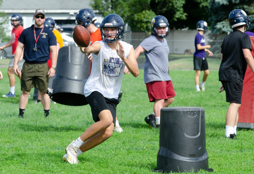 Barrington High School quarterback James Anderson flips the ball to a back during a drill on the first day of preseason football practice on Monday morning, Aug. 23.