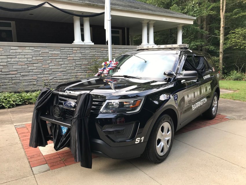Barrington Police Sgt. Gino Caputo's cruiser is draped in black cloth and flowers rest on the windshield. Sgt. Caputo died on Saturday morning, Sept. 11, after a five-week battle with Covid-19.