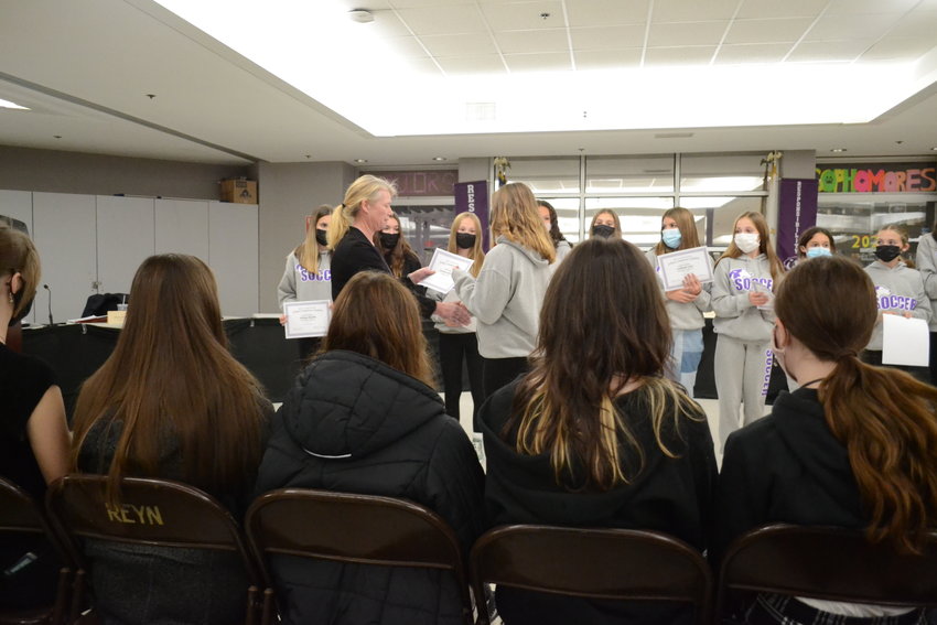 School Committee Vice Chairperson Tara Thibaudeau, unmasked, shakes the hands of members of the Kickemuit Middle School girls&rsquo; soccer team during the committee&rsquo;s recognition ceremony for their second-place finish during the season.