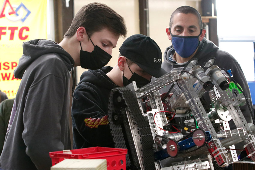 Simon Thibault (left) Miles Kindness and instructor Ryan Garrity work on their robot.