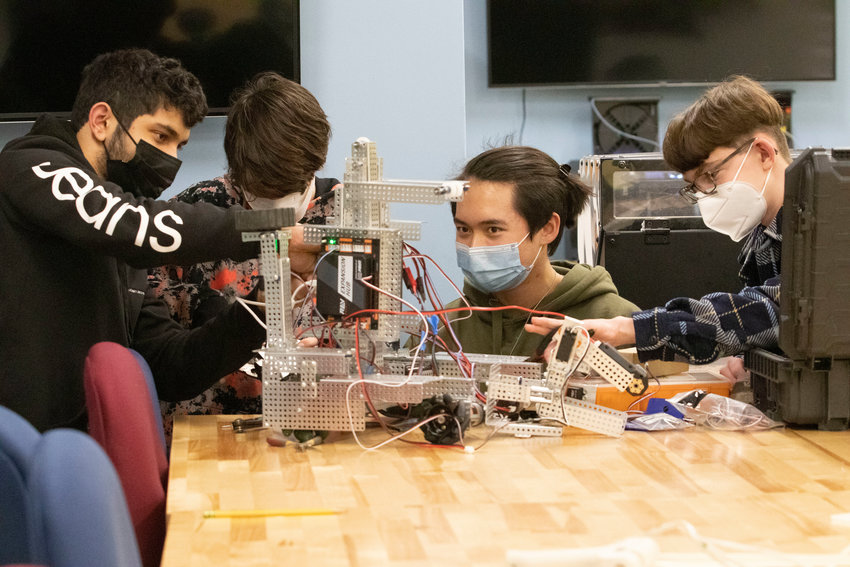 Heider Al-Chalabi (left), Simon Robbins, Michael Cancilliere and Jacob Dickstein work on L1NU5 during a recent robotics team practice at Barrington High School.