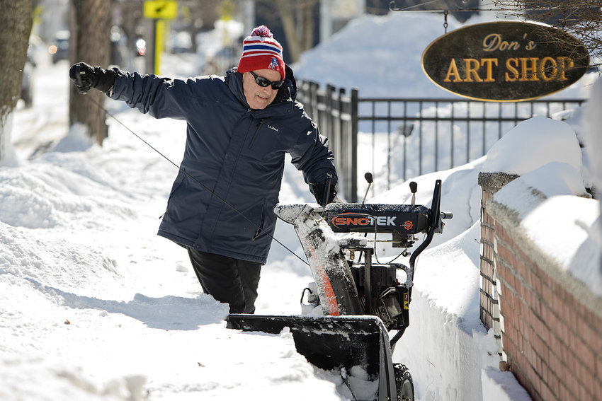 Raymond Rodrigues attempts to restart his snowblower while clearing a Main Street sidewalk on Sunday.