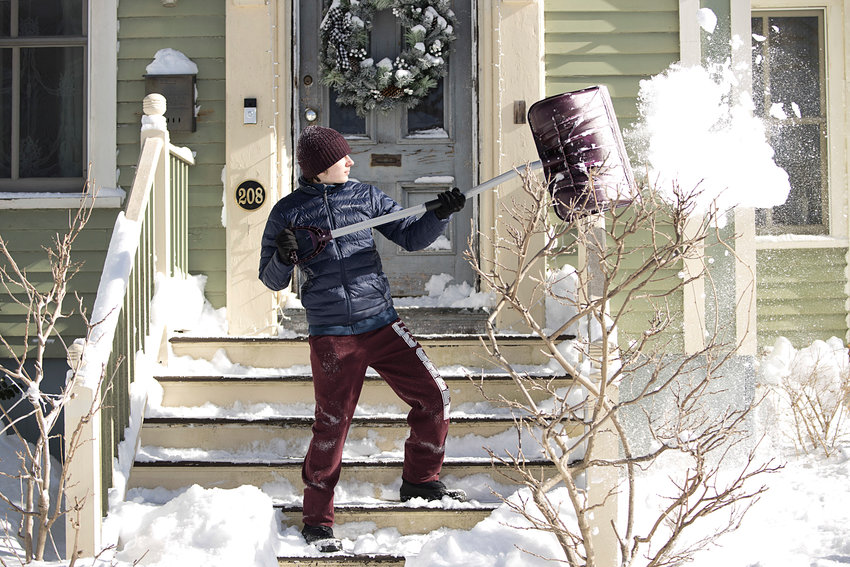 Grange Garcia tosses snow off of the steps of a home on High Street on Sunday.