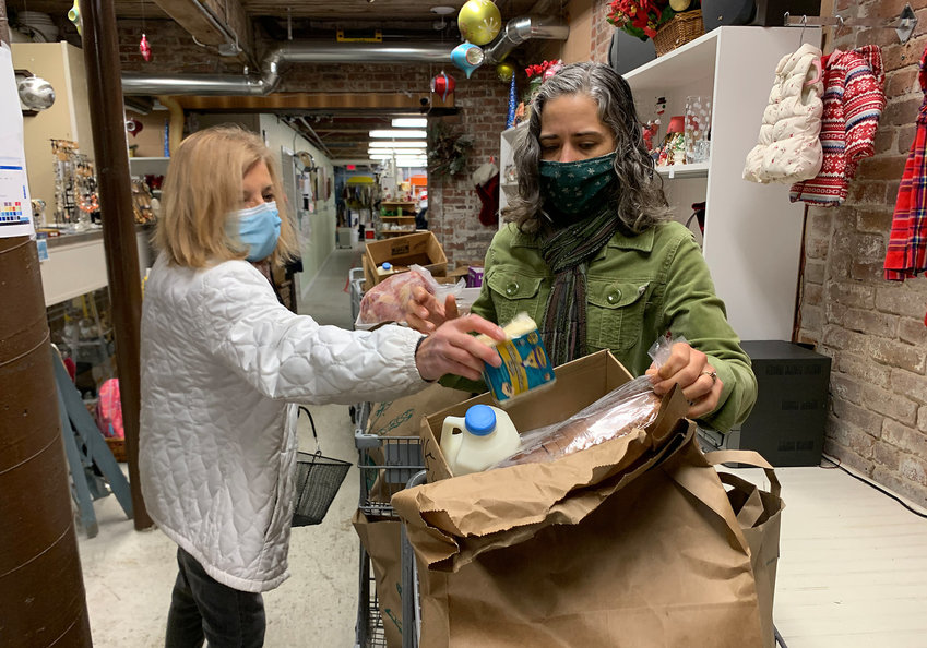 Volunteer Louise Dion (left) brings meat and poultry items to East Bay Food Pantry Executive Director Karen Griffith to ready a food cart for a client, in Dec. 2020, several months into the pandemic. Credit Richard W. Dionne, Jr.