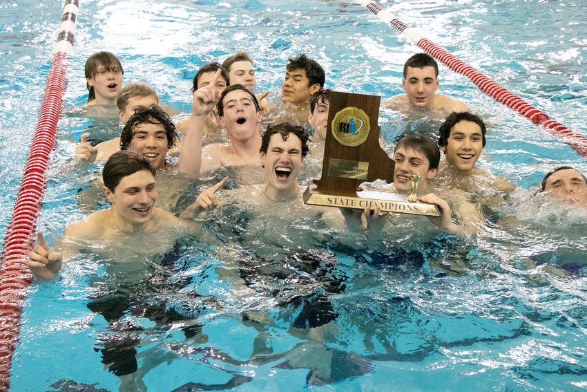 Members of the Barrington High School boys swim team hold their state championship trophy during a dunk in the Brown University pool on Saturday. It was just the second time in more than 30 years that a public school team defeated Hendricken in the state championship meet.