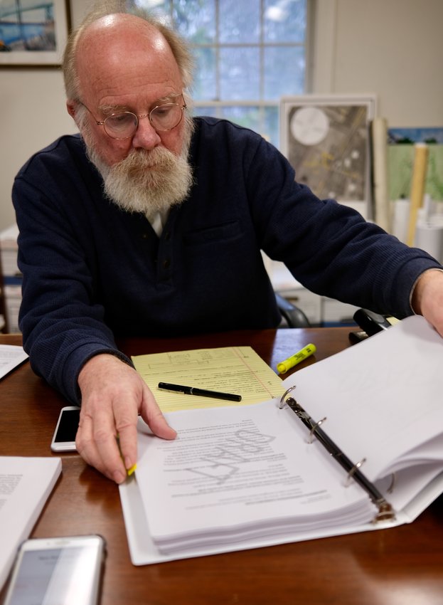 Town Planner Gary Crosby, here thumbing through the draft of the Comprehensive Community Plan, has announced his retirement at he end of the fiscal year, after 18 years of service.