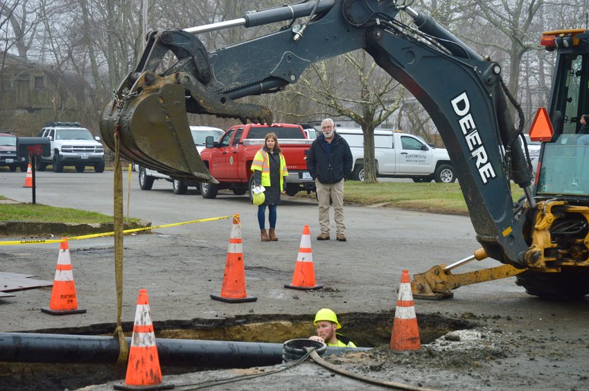 Jessica Lynch, general manager and chief engineer of the Portsmouth Water and Fire District (PWFD), and Brian Woodhead, director of the Department of Public Works (DPW), watch as a water main is guided into a ditch dug into the town access road between the police and fire departments and DPW building last Thursday.