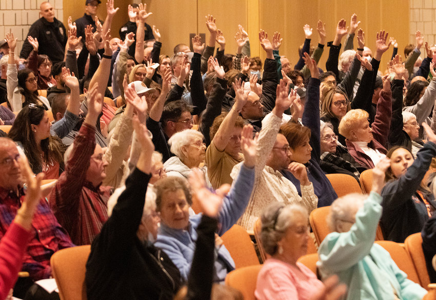 Voters raise their hands to vote in favor of helping to fund the new Diman School project in Fall River.&nbsp;