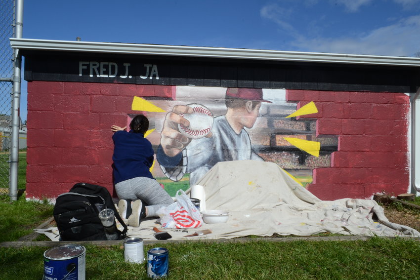 Jordan Scriven works on the mural at Jannito Field on Monday afternoon. She said she would be finished with it by the end of that day.