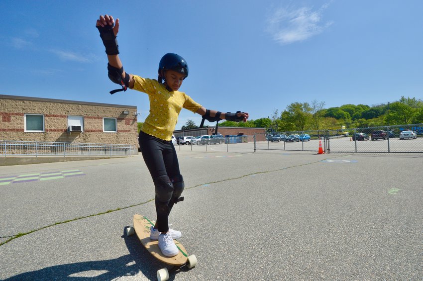 Fourth-grader Keiley balances on the longboard during gym class at Melville School on Monday.