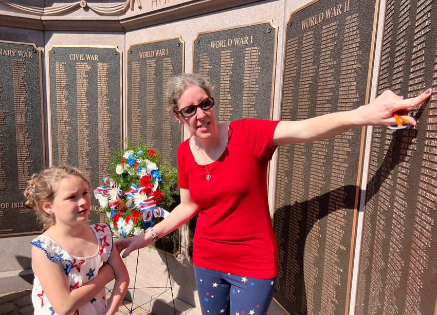 Nicole Tvrdik finds shows her daughter, Evelyn, 6, the names of her relatives Joseph La Roche, a WWII vet, and Wilfred La Roche, a WWI vet, on the Warren Honor Roll at the Town Common after the Memorial Day ceremony on Monday.