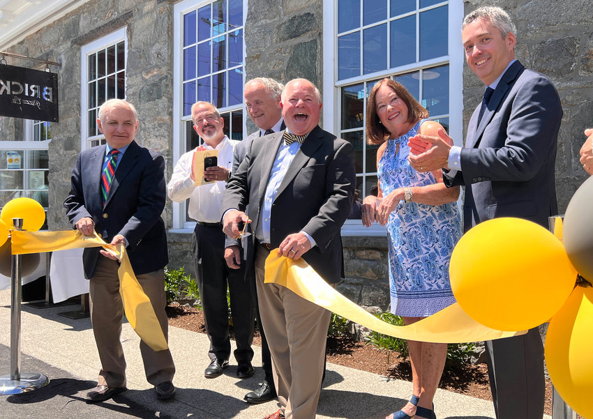 Senator Jack Reed, Town Council President Nathan Calouro, Joseph Brito, Jr. and his wife Betty, town administrator Steven Contente and others gather as Brito cuts a ribbon in front of the Brick Pizza Co. on Friday.