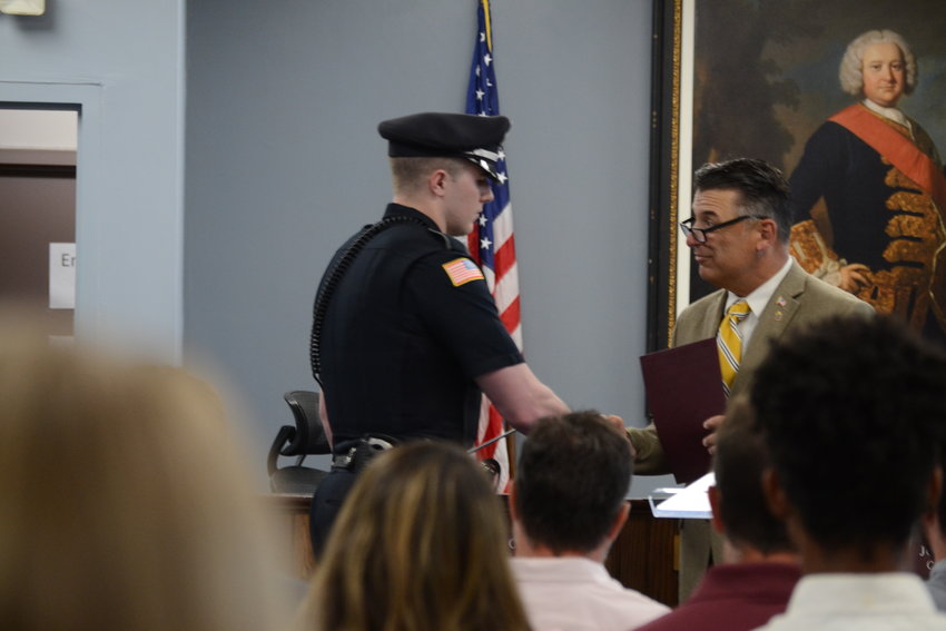Patrolman Lane Ukura receives a commendation from Town Council Vice President Steve Calenda following action he took during a house fire on April 16, 2022.