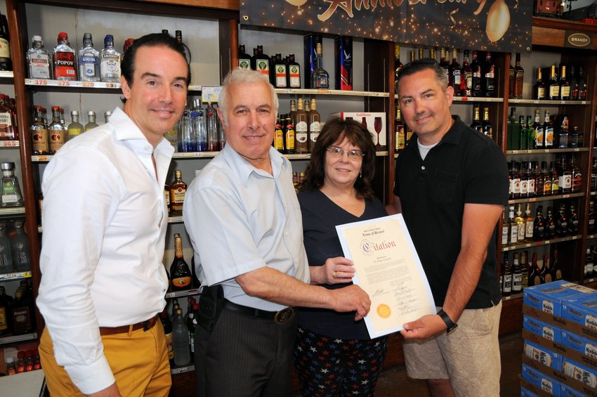 Jose and Dolores Teixeira (center) were honored by the Town of Bristol this past week in recognition as owners of the Mt. Hope Liquor Store, which celebrated its 40th anniversary. Making the citation presentation were Town Councilmen (Tim Sweeney (far left) and Aaron Ley (right).