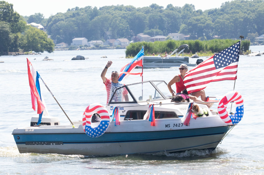 Boaters taking part in Saturday's parade on South Watuppa Pond wave to well-wishers on shore.