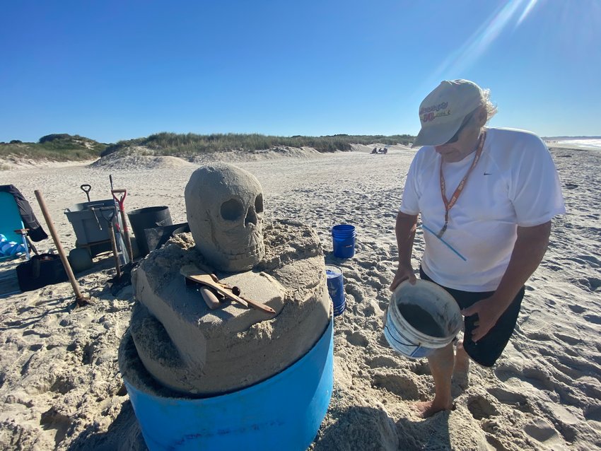 Richard Huggins lays the groundwork for his skull and books sculpture early Friday morning at Cherry and Webb beach.