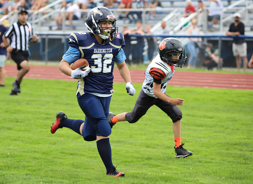 Barrington running back Eddie Wong sprints past a Taunton defensive back during a long touchdown run early in the 12U game.