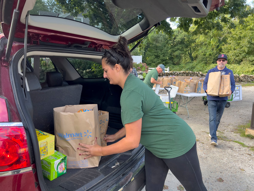 Courtney Rocha places a bag of groceries into a trunk as the food bank doles out their weekly food pick up.&nbsp;    Pastor Seth Fortier is right.