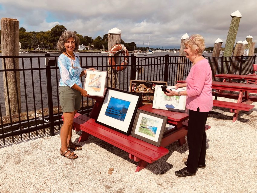 Sally Barker and Jane Harrison admire artwork donated by local artists that is destined for the silent auction at Warren Heritage Foundation&rsquo;s Portside Picnic.