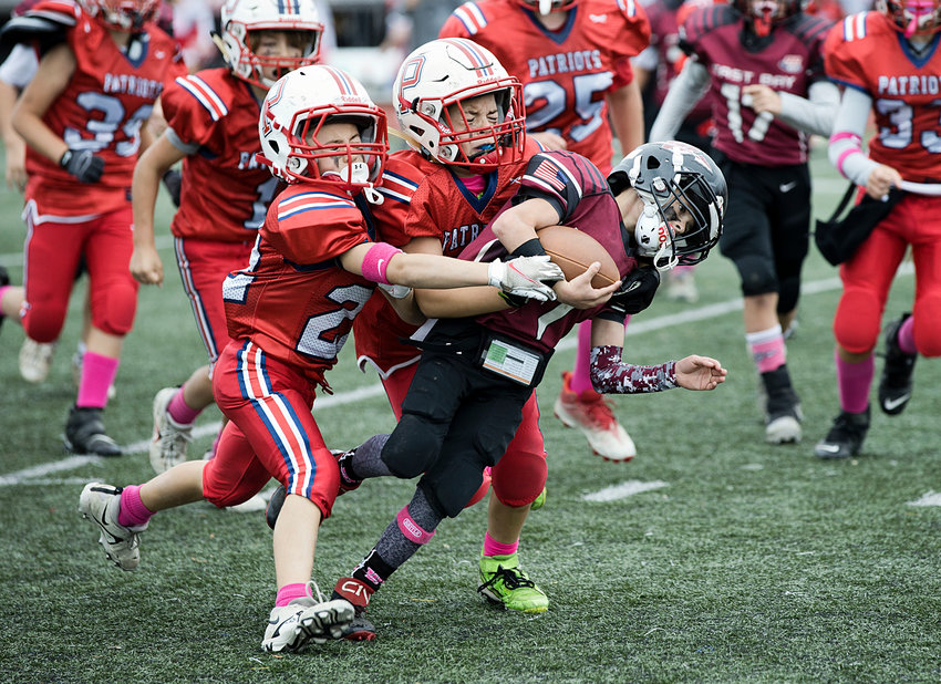 The Patriots&rsquo; Mitchell Silvia (left) and Romeo Prestipino stop East Bay&rsquo;s Cam Ferreira from advancing the ball in Sunday&rsquo;s Pop Warner 10U quarterfinals, won by Portsmouth.