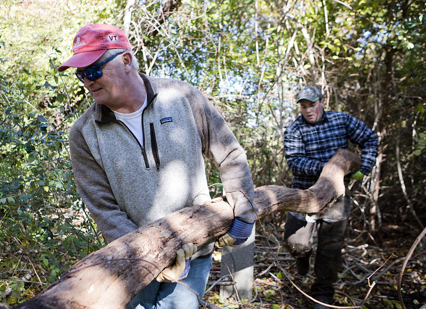 Craig Clark (left) and Nathan Minese carry a large limb out of an area while cleaning up Butts Hill Fort on Saturday. About 20 people took part in the fourth volunteer cleanup of the fort.