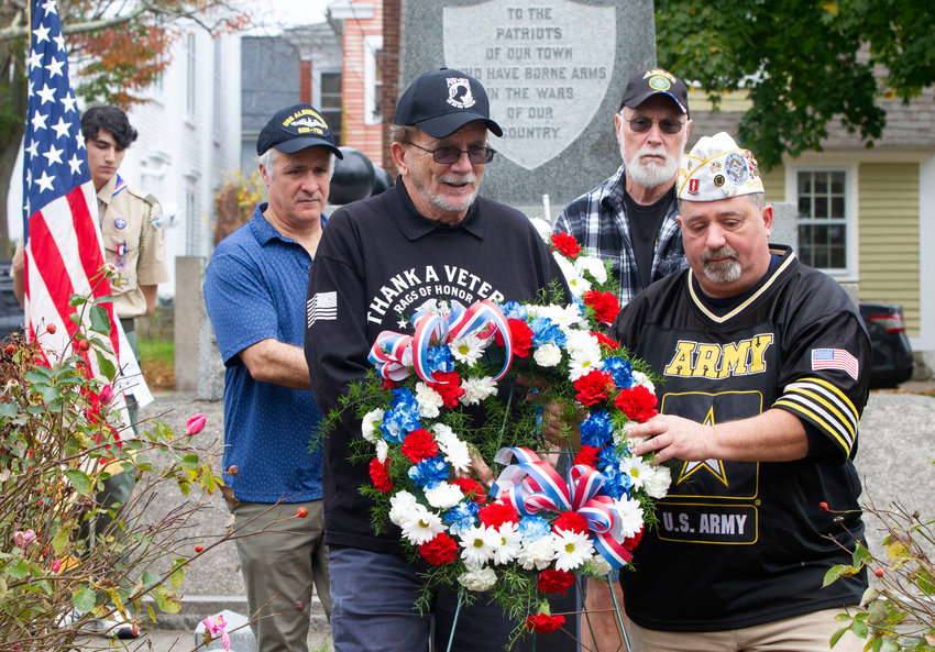 Dave McCarthy (left) John Cianci carry memorial wreath (front) and Rep Jason Knight and John LaDuke carry a second wreath (back) to be placed at the war memorial during the ceremony.